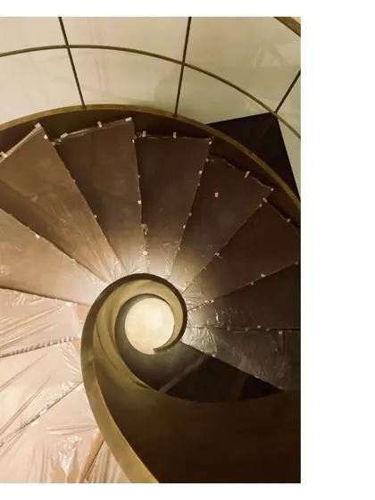 An overhead view of the spiral staircase, showing the perfect geometry of the aged brass ribbon as it winds its way up. This is a testament to the precision of our craftsmen.