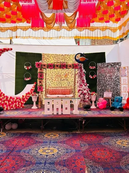 A full stage view of a traditional Dohale Jevan baby shower. The setup includes a decorated swing, a large floral moon, character cutouts, and maternity photos on easels.