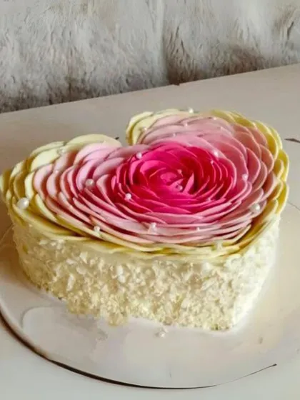 A beautiful heart-shaped cake with intricate pink and white ombre petals, creating a stunning floral effect.