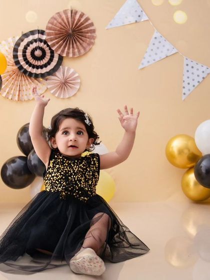 This little girl is reaching for the stars in her sparkly black dress, part of a fun and dynamic travel-themed setup.