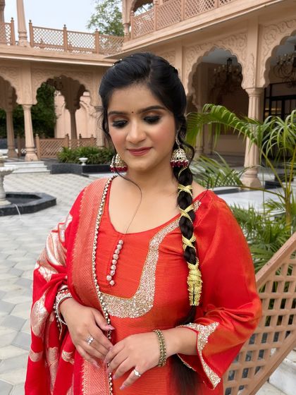 A full view of the client in her beautiful red suit, with makeup and hair perfectly styled for a festive occasion.