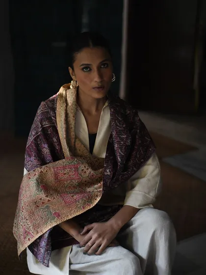 A moody, atmospheric portrait for House of Wandering Silk. The model is wrapped in a luxurious, intricately woven shawl.
