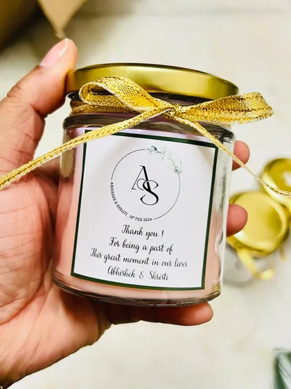 We love making your wedding favors feel personal. This is a close-up of a scented soy candle we customized with the couple's initials and a thank you message, finished with a delicate golden ribbon.