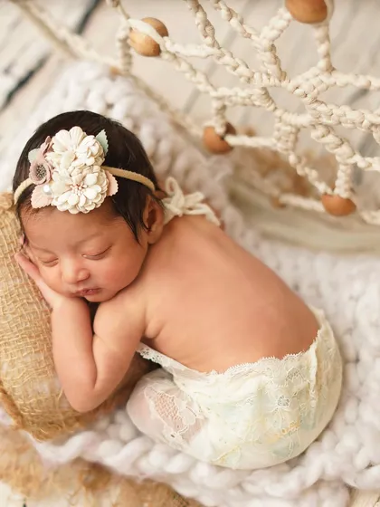 A sweet side profile of the newborn in her boho-chic setup, highlighting her delicate features and lace outfit.