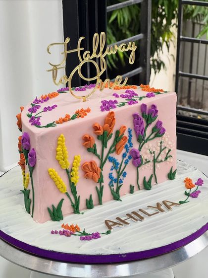 Halfway to One and already blooming with colors! This unique half-cake is decorated with a garden of hand-piped buttercream flowers to celebrate a six-month milestone.