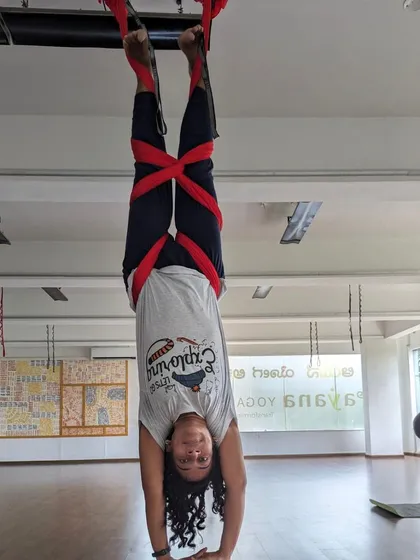 An inverted student smiles for the camera during a weekend aerial session. The studio is always buzzing with energy.