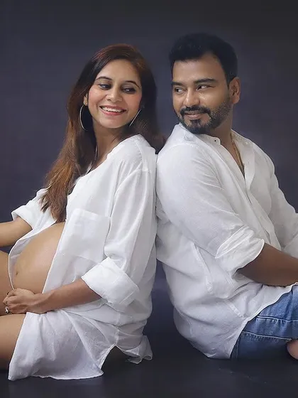 A playful and happy moment between the couple. The casual white shirts and the genuine smiles make this studio maternity photo feel so authentic and full of joy.