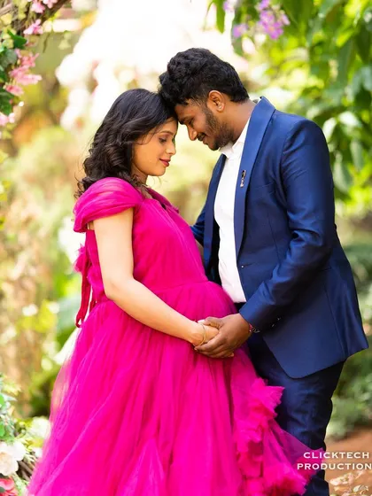 A beautiful maternity portrait with a flowing pink gown in a floral garden setting.