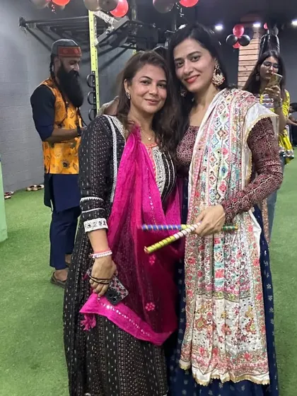 Two members show off their colorful dandiya sticks and traditional attire during our Navratri celebration.