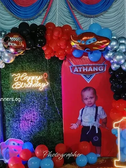A dynamic Disney Cars first birthday theme with a road-like backdrop and a stop sign prop.