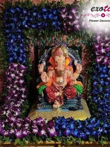 A striking and modern Ganpati backdrop using a gradient of deep blue and purple orchids. The rich colors and exotic flowers create a unique and visually captivating frame for the idol, offering a contemporary twist on festival decor.