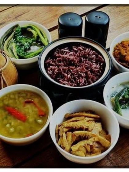 A traditional Naga meal setup featuring organic black rice. It is served with different side dishes like boiled greens, dal, and a chicken curry, offering a wholesome and authentic experience.