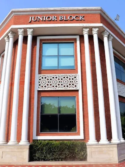 The Junior Block of Prayag International School showcases a fusion of classical and modern design. The facade features red brick, grand white pillars, and intricate jali work for a distinguished look.