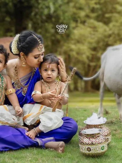 A mother's love captured in a single frame, as she holds her two little Krishnas, one looking curious and the other content.