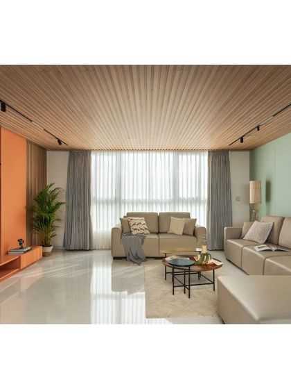 The living room in the House Above The Tree features a slatted wood ceiling and a soft, neutral color palette. The full-height windows and sheer curtains allow for ample natural light while maintaining privacy.