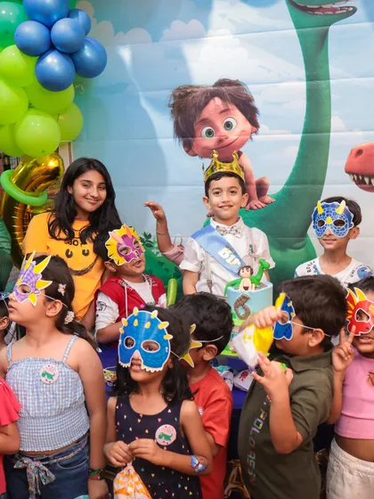 The birthday boy, wearing a crown, surrounded by his friends in fun dinosaur masks. These are the joyful, memorable moments we love to create.