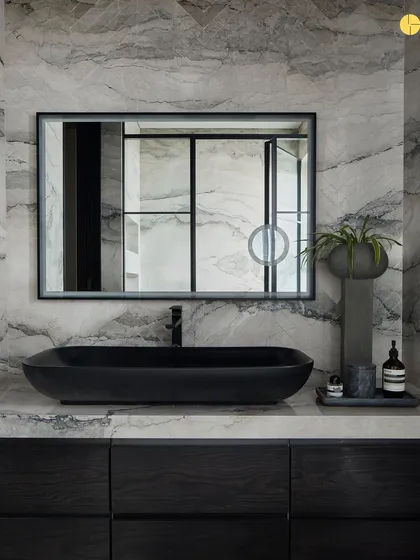 The powder room in 'Pad by the Bay' is a study in dramatic elegance. Wall-to-wall marble with striking veins is paired with a sleek black basin and vanity, creating a bold and luxurious statement in a small space.