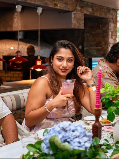 A guest enjoys a pink cocktail, surrounded by the beautiful floral arrangements of our brunch.