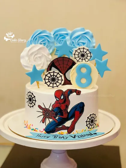 An action-packed Spiderman cake for an 8th birthday. It's decorated with spider webs, stars, and blue and white roses for a cool and stylish superhero theme.