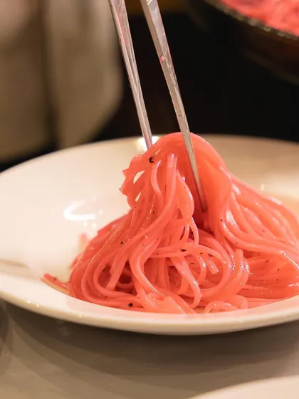 A chef plating vibrant pink pasta for our Galentine's dinner. The color was a key part of the fun, diva-inspired theme of the evening.