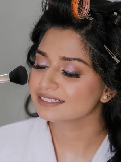 A behind-the-scenes shot of the bride getting her makeup done for her white wedding.