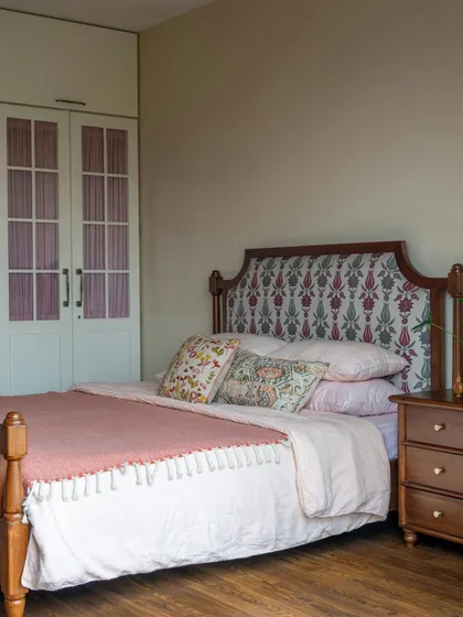 This bedroom shows how a simple pattern on the headboard and wardrobe doors can add character to a space. The soft pink and green tones create a gentle, soothing atmosphere, perfect for a personal sanctuary.