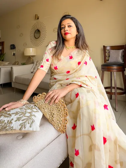 A full view of the modern Jamdani saree, showing the beautiful lotus motifs woven into the fabric. The jute clutch adds a lovely, rustic touch.