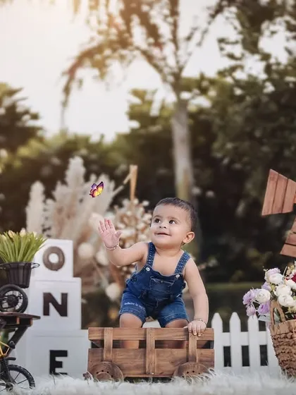 A beautiful, wide shot of a rustic farm-themed outdoor setup. This little boy is captivated by a butterfly, creating a magical and candid photograph.