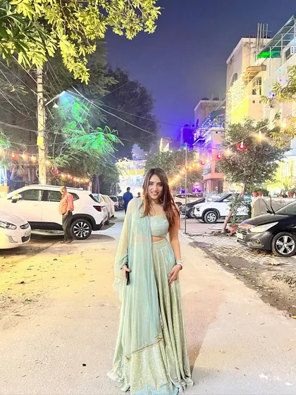A festive look on a city street in a light green lehenga. This shows how to style ethnic wear for a Diwali party or other urban celebration.