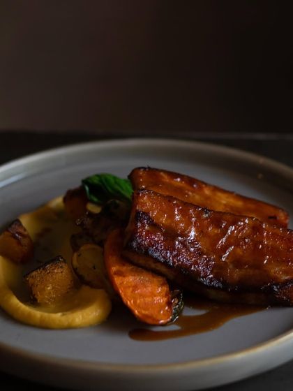 Indulge in our melt-in-your-mouth Sticky BBQ Pork Belly. It's slow-cooked until tender and served with a sweet charred onion and apple purée, crispy potatoes, and crunchy pork crackling.