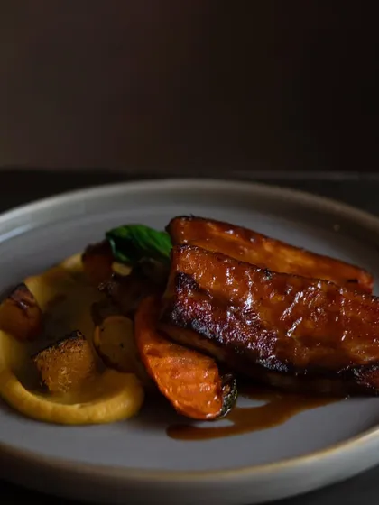 Indulge in our melt-in-your-mouth Sticky BBQ Pork Belly. It's slow-cooked until tender and served with a sweet charred onion and apple purée, crispy potatoes, and crunchy pork crackling.