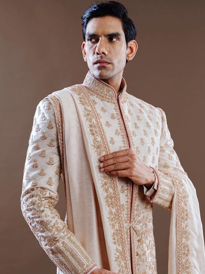 This sherwani features delicate gold embroidery on an ivory base, paired with a matching stole. It is a perfect example of our commitment to creating ensembles of understated and timeless elegance.
