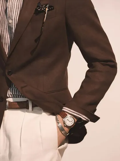 A stylish combination of a brown blazer, striped shirt, and white trousers. We help our clients build versatile wardrobes with pieces that work together seamlessly.