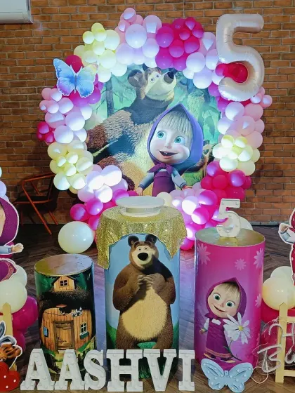 An elaborate Masha and the Bear 5th birthday party. This setup includes multiple character cutouts, themed plinths, and a circular balloon arrangement, bringing the cartoon to life.
