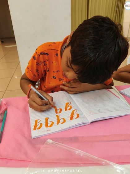 Intense concentration from this young boy as he practices his 'b's. Practice is essential for mastering the flow of brush calligraphy.