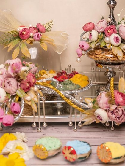 A luxurious silver-themed Holi hamper, complete with floral arrangements, platters of sweets, and elegant serveware. Perfect for a sophisticated Holi party.