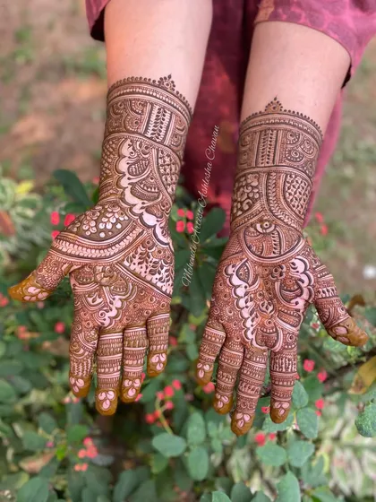A full-coverage mehendi design with a mix of traditional patterns. The design is set against a natural backdrop, highlighting the beauty of the henna.