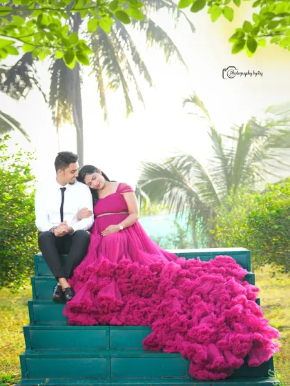 A romantic couple's portrait on green steps, surrounded by flowers. The mother-to-be's wine-colored ruffled gown is the highlight.