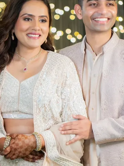 This couple's Sangeet look is pure elegance. The bride's makeup is soft and glowing, with her hair in romantic waves, perfectly matching the dreamy, fairy-light ambiance.