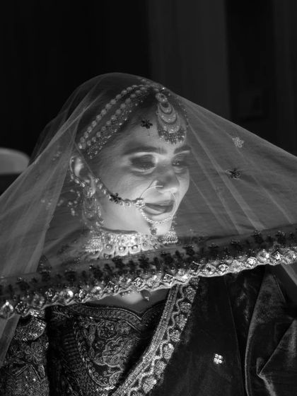 An artistic black and white photo of the bride under her veil. This shot highlights the contouring and structure of the makeup, proving it looks dramatic and beautiful even without color.