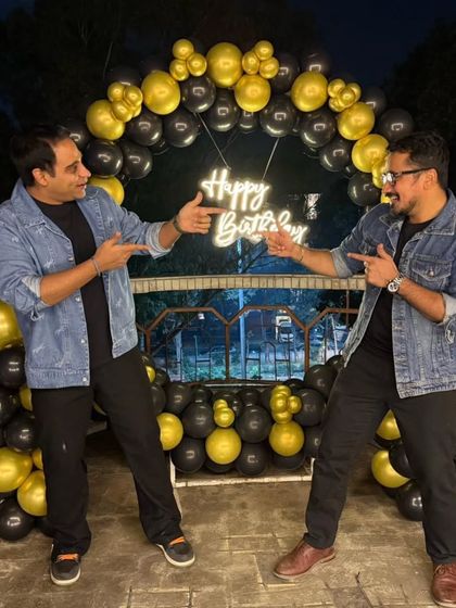Clients enjoying their black and gold themed terrace party, posing for a photo in front of the circular balloon arch.