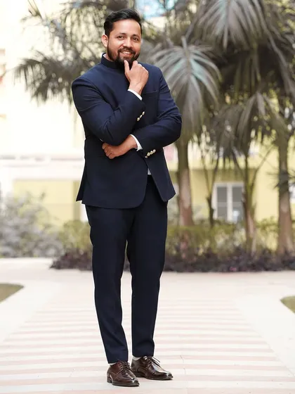 A stylish full-length portrait of the groom in a classic Jodhpuri suit. His thoughtful pose adds a touch of sophistication.