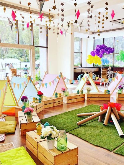 An indoor "glamping" party with individual tents, a faux bonfire, and star decorations hanging from the ceiling for a night of adventure under the stars.