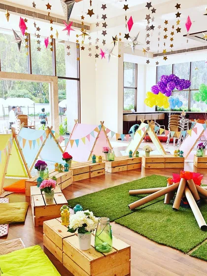 An indoor "glamping" party with individual tents, a faux bonfire, and star decorations hanging from the ceiling for a night of adventure under the stars.