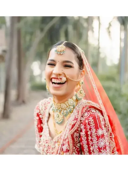The purest expression of joy. This bride's unrestrained laughter is infectious, a candid moment that shows the happiness and excitement of the wedding day, beautifully complemented by her traditional red attire.