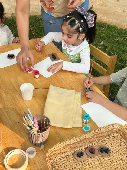 Little artists focused on their work. At this bug-themed party, children are painting clay models of insects, learning about their shapes and colors while creating their own to take home.