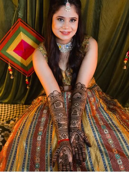 A happy client showing off her intricate bridal mehendi while wearing our multi-color striped lehenga.