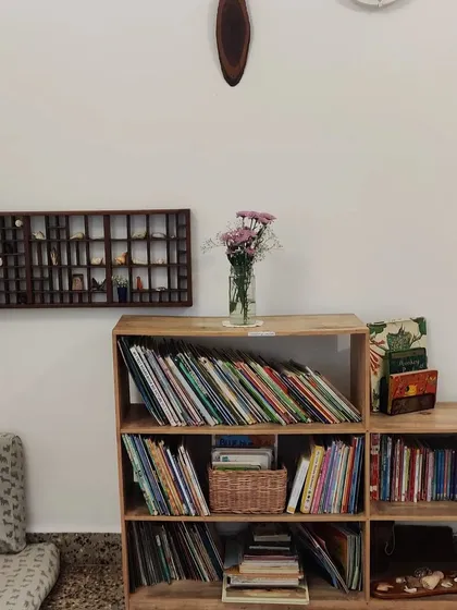 A quiet corner of our primary environment. The shelves hold a curated collection of books and natural objects like shells and seed pods, sparking curiosity and inviting closer inspection.
