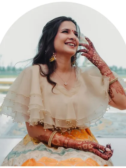 Another happy moment showcasing the bride's beautiful henna and the contemporary design of her cape blouse and colorful lehenga.
