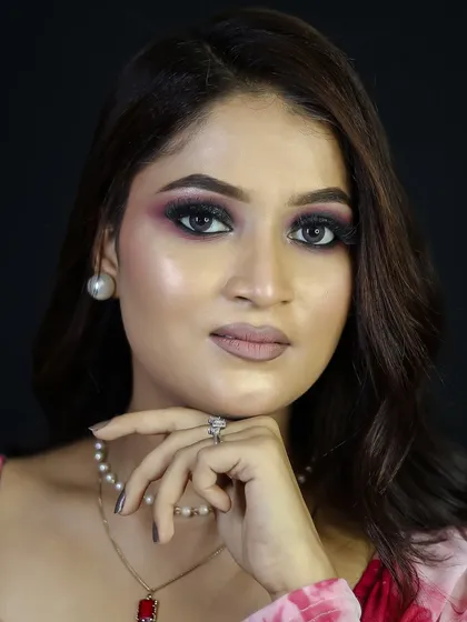 A confident portrait of the model, showing the full makeup and pearl accessories.